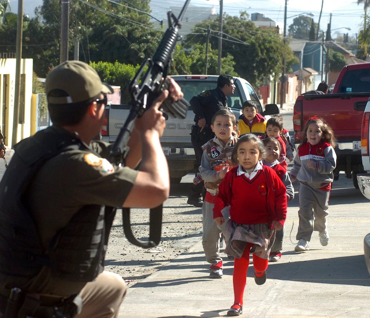 Fotografía cedida del 2008 que muestra a policías federales mexicanos poniendo a salvo a un grupo de niños, durante un tiroteo en el que participaron agentes federales y soldados contra sicarios en la ciudad mexicana de Tijuana. (Foto Prensa Libre: EFE)