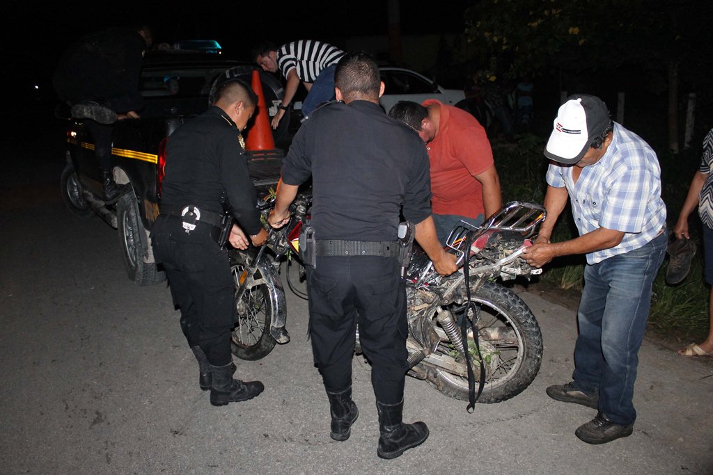 Agentes de la PNC inspeccionan la motocicleta en la que viajaba la pareja, en El Chal. (Foto Prensa Libre: Walfredo Obando)