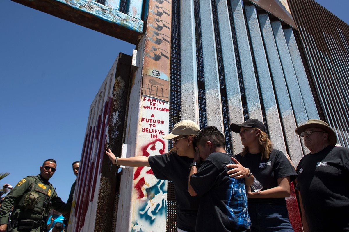 Familias se despiden de sus seres queridos, después de haberse abrazado, en la frontera entre Tijuana, México, y San Diego, EE. UU. (Foto Prensa Libre: AFP)
