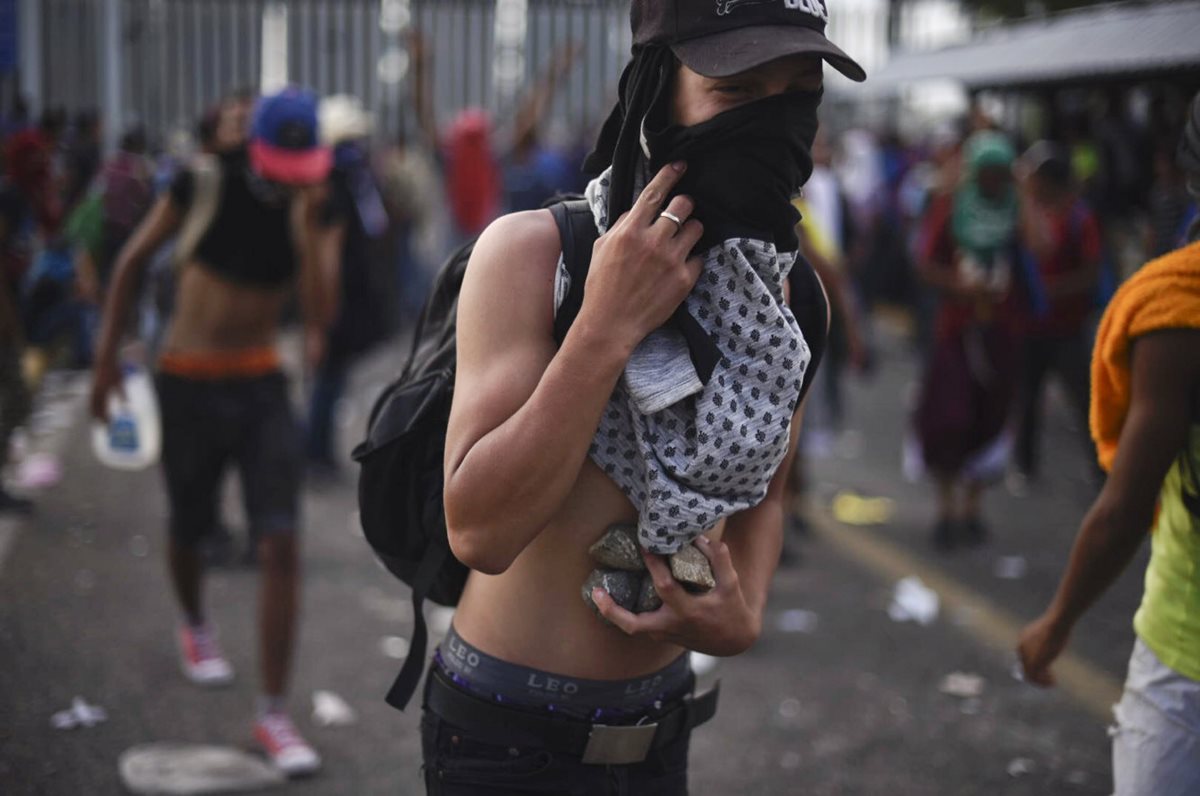 Un migrante hondureño con piedras, durante los disturbios el domingo último en la frontera de Guatemala con México. (Foto Prensa Libre: AFP)