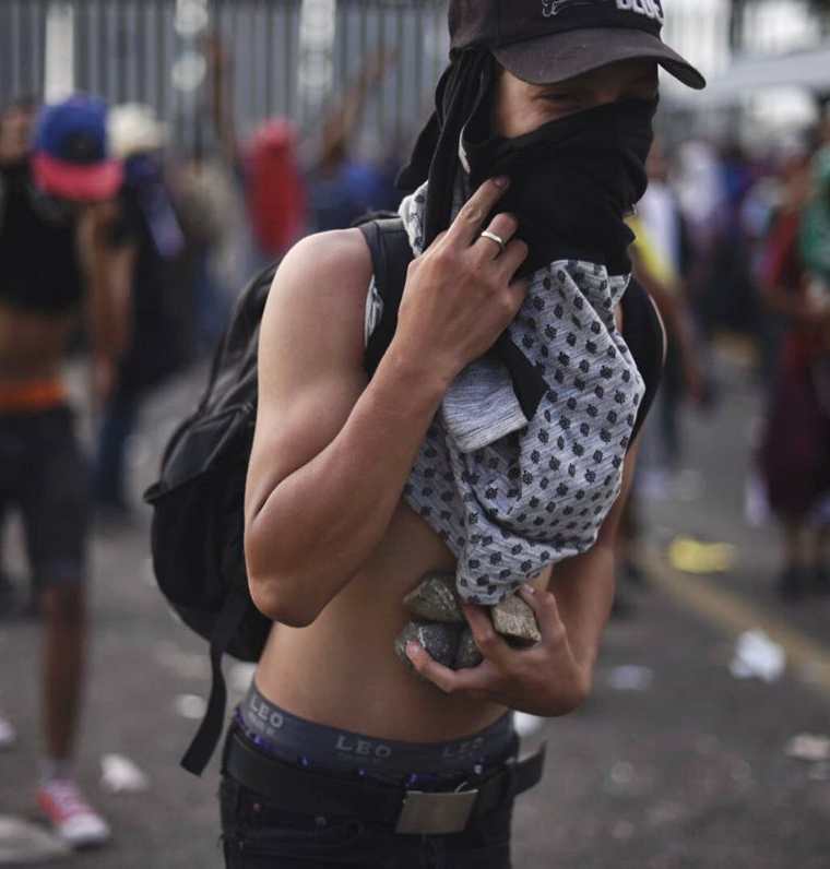 Un migrante hondureño con piedras, durante los disturbios el domingo último en la frontera de Guatemala con México. (Foto Prensa Libre: AFP)