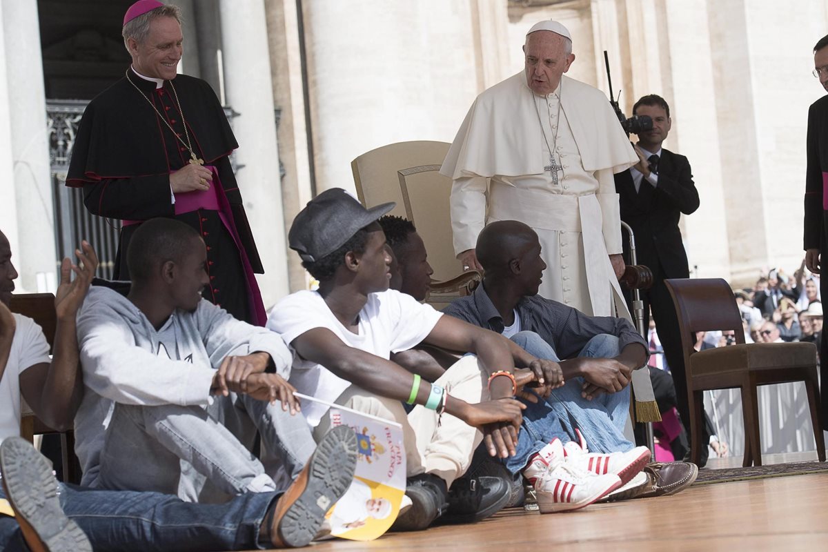 El papa Francisco observa a los refugiados que invitó a subir al escenario durante su audiencia general en el Vaticano. (Foto Prensa Libre: EFE).