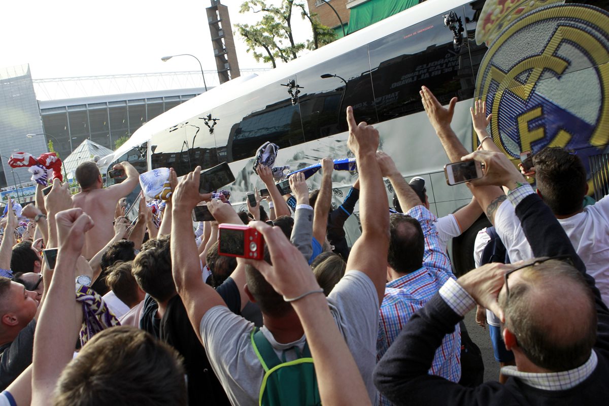 Los seguidores del Real Madrid aplauden el paso del bus de su equipo.