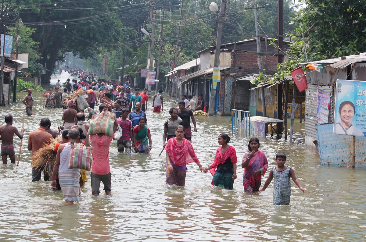 Una pareja busca sus pertenencias tras las inundaciones en el distrito de Morigaon, en Assam India.(Foto Prensa Libre: EFE)