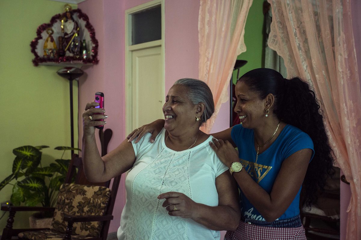 Yolanda Mollinedo mira a su nieta Alejandra en Virginia, EE. UU., en su smartphone usando una app de videochat junto a su sobrina Yulisleidi, con nuevo servicio experimental de internet en su casa en La Habana, Cuba. (Foto Prensa Libre: AP).