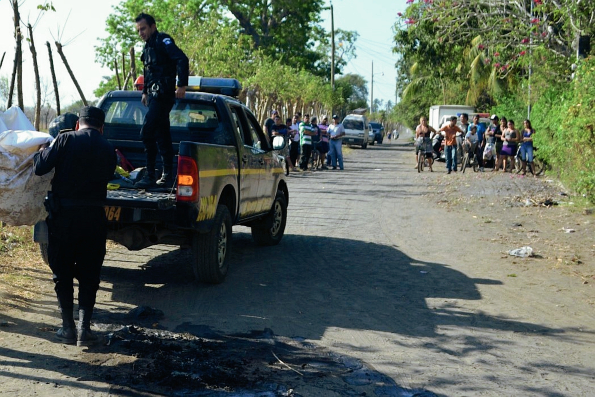 Agentes de  la PNC trasladan cadáver calcinado de un hombre en Puerto San José, Escuintla. (Foto Prensa Libre: Carlos Enrique Paredes)