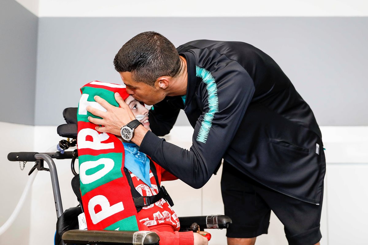 Cristiano Ronaldo besa la frente de Joao, uno de los dos niños con los que se reunió gracias a la ayuda de Make a Wish. (Foto Prensa Libre: EFE)