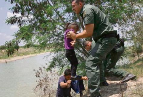 Una niña  es rescatada por agentes después al cruzar el río en la  frontera entre México y EE. UU. Cientos de migrantes indocumentados,  muchos de ellos niños, han llegado de manera ilegal a EE. UU., lo cual  ha causado una crisis humanitaria.