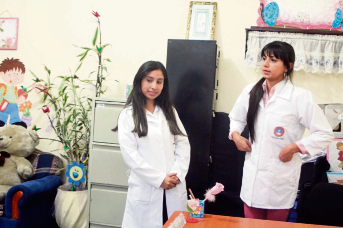 Dos estudiantes brindan información de la atención gratuita que brindan en Cobán.