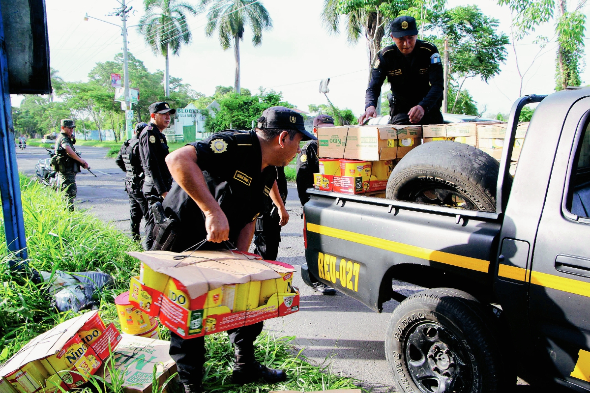 Agentes de la PNC y soldados suben a palangana de autopatrulla la mercadería decomisada en la ciudad de Retalhuleu. (Foto Prensa Libre: Rolando Miranda)