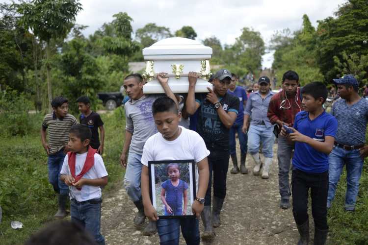 Un niño muestra una foto de Jakelin Caal, mientras encabeza el funeral, en Raxruhá, Alta Verapaz.