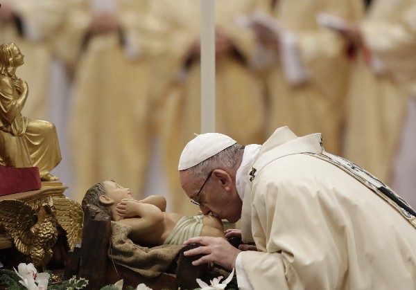 El Papa Francis besa una essultura del Niño jesús mientras celebra la misa en El Caticano. (AP).