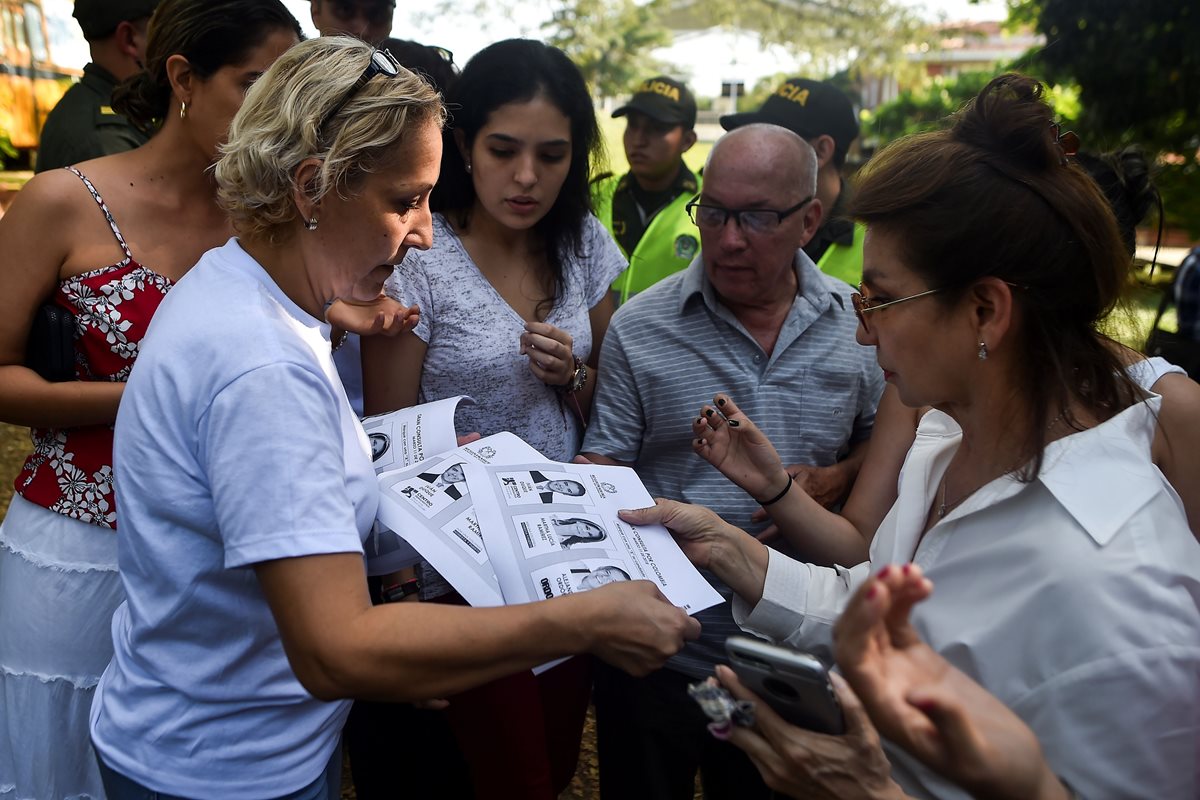 Una mujer reparte fotocopias de las papeletas para uno de los dos bloques políticos principales que celebran elecciones primarias al mismo tiempo que las elecciones parlamentarias en Colombia. (Foto Prensa Libre:AFP).