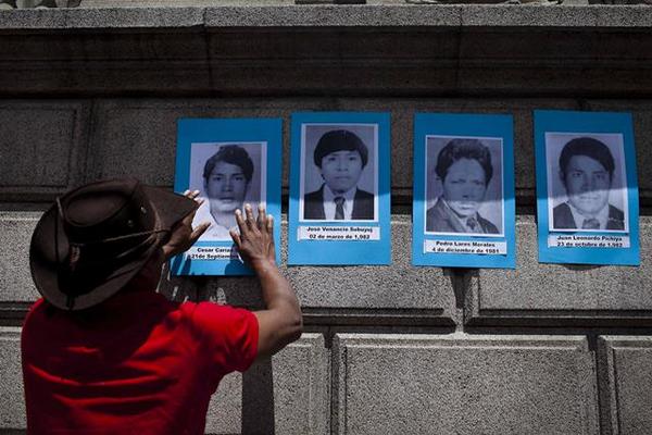 Colocan imágenes de desaparecidos durante la guerra (1960-1996) durante una marcha para expresar que sí existió genocidio en Guatemala. (Foto Prensa Libre: EFE)