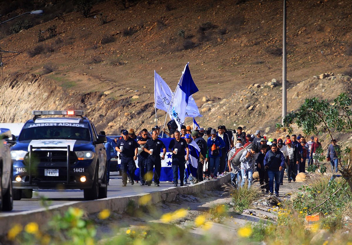 Migrantes marchan desde los albergues hasta la embajada de EE. UU. en Tijuana, escoltados por autopatrullas. (Foto Prensa Libre: EFE)