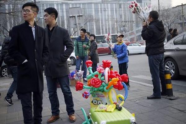 Vendedores de flores y globos ofrecen sus productos a peatones en China por la celebración del Día del Cariño. (Foto Prensa Libre: EFE)
