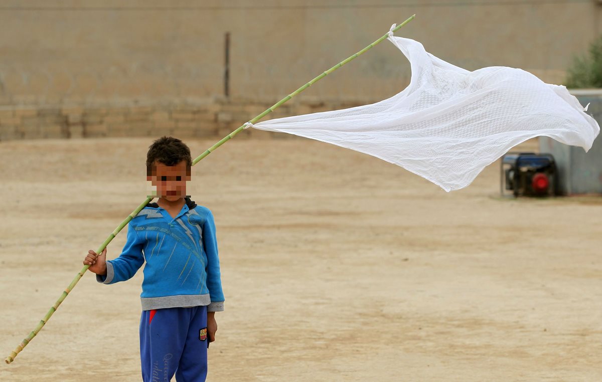 Un niño iraquí desplazado posa con una bandera blanca en señal de paz en el sur de Mosul. (Foto Prensa Libre: AFP).