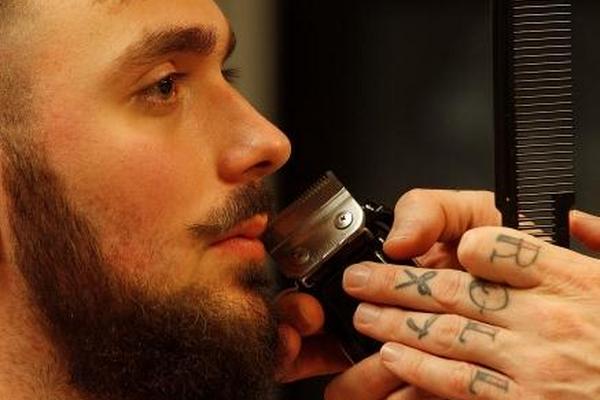 El barbero español Salvador Chanza demuestra sus habilidades en la barba de sus clientes, en Polonia. (Foto Prensa Libre: AP)