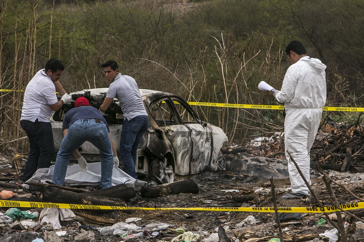 Forenses recaban evidencias en el vehículo que fue hallado en el lugar. (Foto Prensa Libre: EFE).