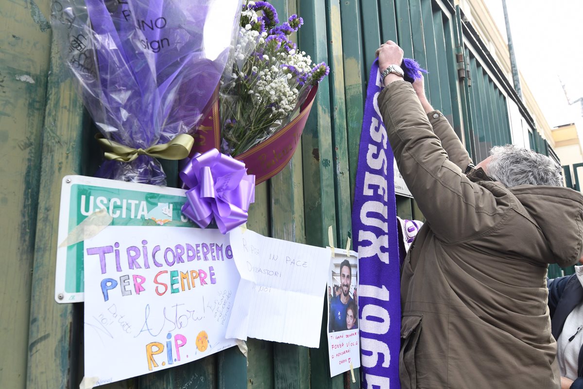 Una seguidora de la Fiorentina coloca una bufanda de Astori en una de las puertas del estadio. (Foto Prensa Libre: AFP)