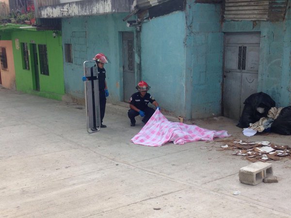 Bomberos Municipales cubren el cuerpo del hombre muerto a balazos este domingo en la zona 6. (Foto Prensa Libre: CBM)