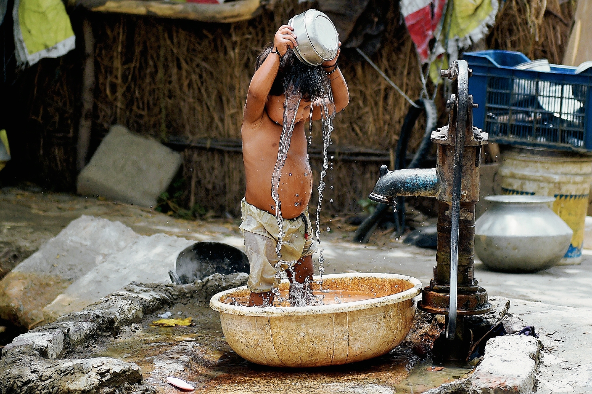 Un niño se baña para refrescarse por el intenso calor en Nueva Delhi. (Foto Prensa Libre:AFP).