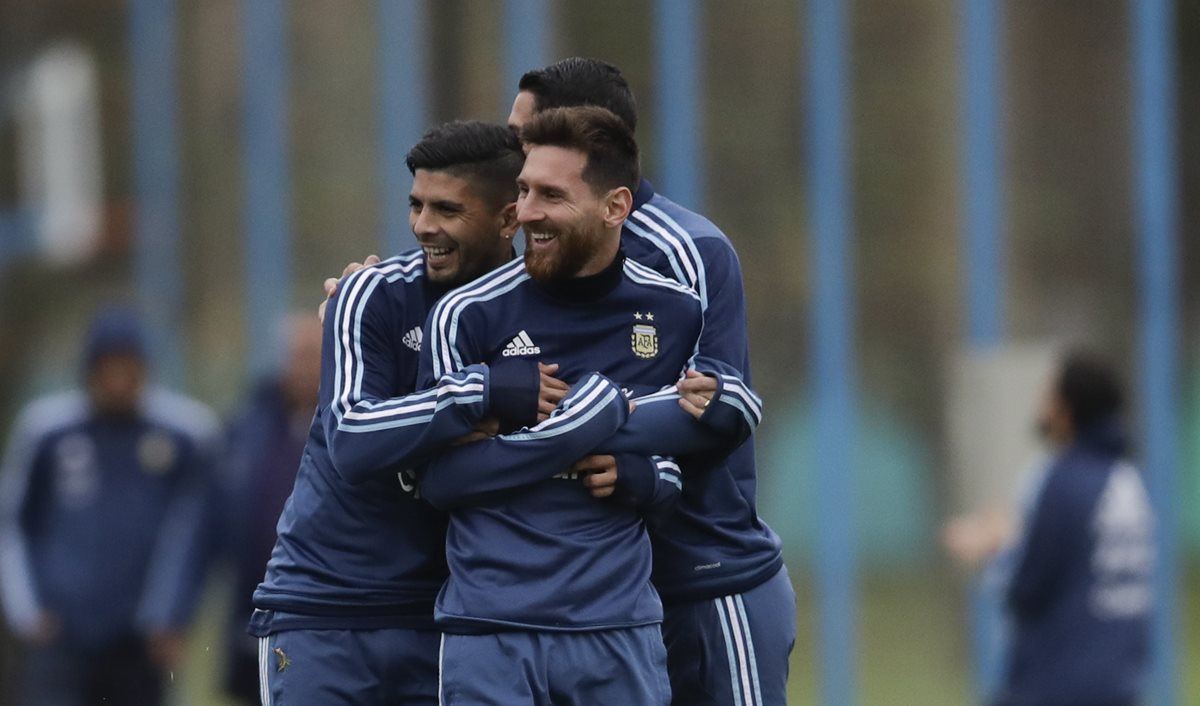Éver Banega y Ángel Di María abrazan a Lionel Messi durante un entrenamiento de la selección de Argentina previo al juego frente a Venezuela. (Foto Prensa Libre: AP)