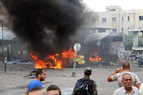 Varios sirios observan la escena del ataque terrorista en la ciudad de Tartus. (Foto Prensa Libre:AFP)