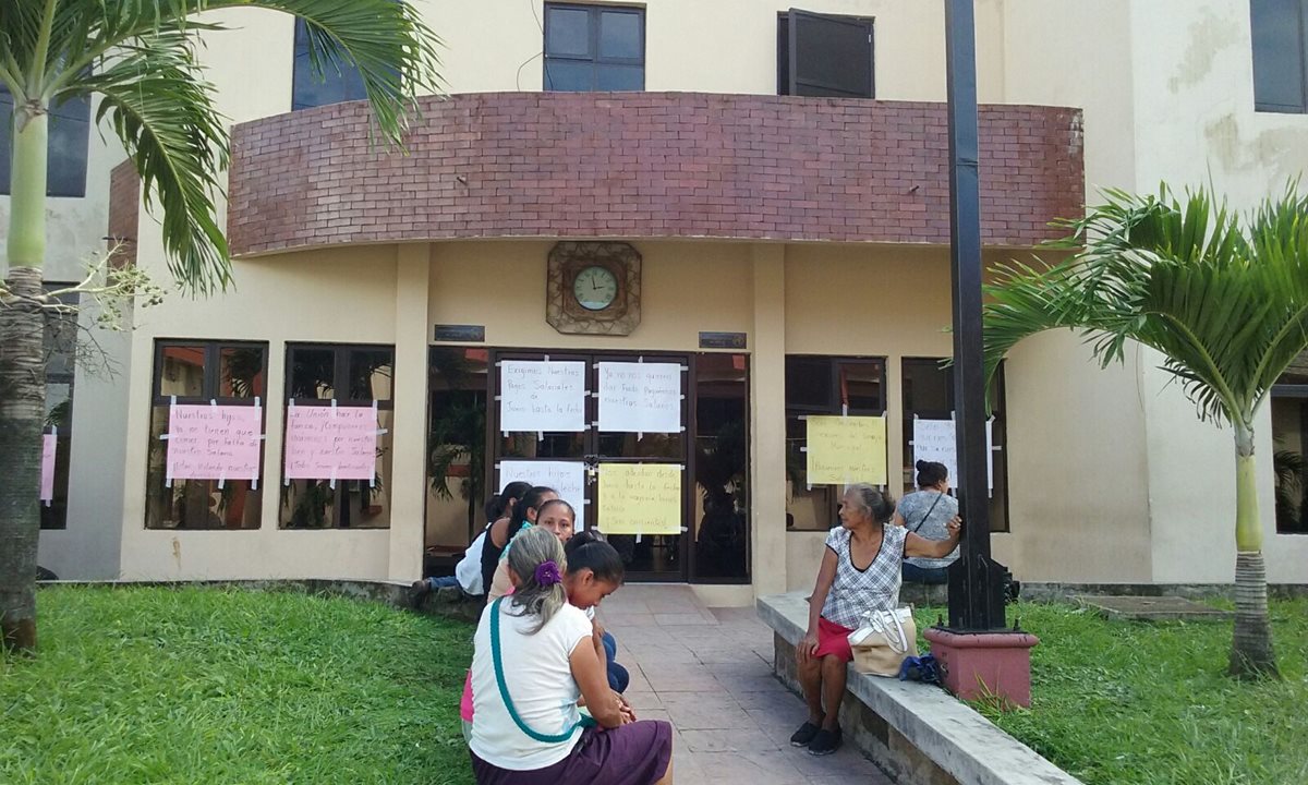 Empleados de la comuna de Melchor de Mencos, Petén, colocan pancartas en las ventanas del edificio para exigir pago de salarios atrasados. (Foto Prensa Libre: Rigoberto Escobar)
