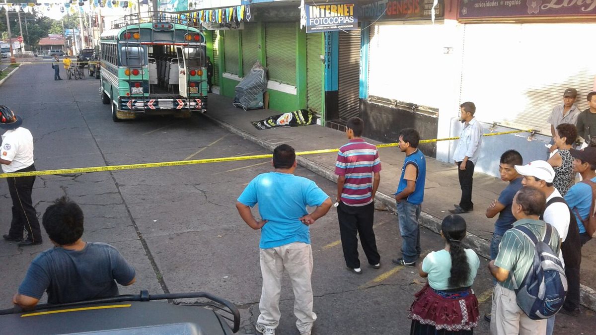 El cadáver de un hombre yace cerca de un autobús en el que laboraba, en la zona 1 de Mazatenango. (Foto Prensa Libre: Melvin Jacinto Popá)