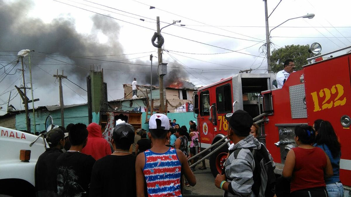 Bomberos tratan de apagar las llamas mientras que los vecinos salen con sus pertenencias. (Foto Prensa Libre)