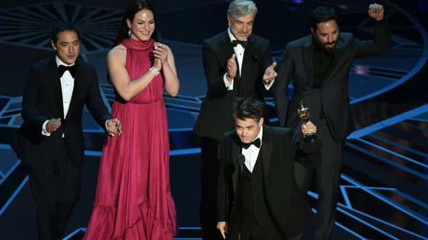 El director Sebastián Lelio recibe el Oscar a mejor película de habla no inglesa acompañado del elenco de "Una mujer fantástica". AFP