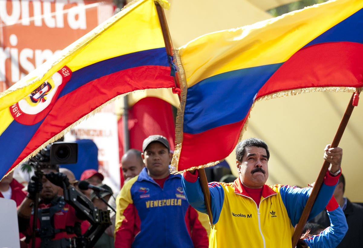 El presidente Nicolás Maduro (derecha), ondea una bandera venezolana durante una marcha de simpatizantes que apoyaron las medidas que el mandatario ha adoptado en la frontera. (Foto Prensa Libre: AP).