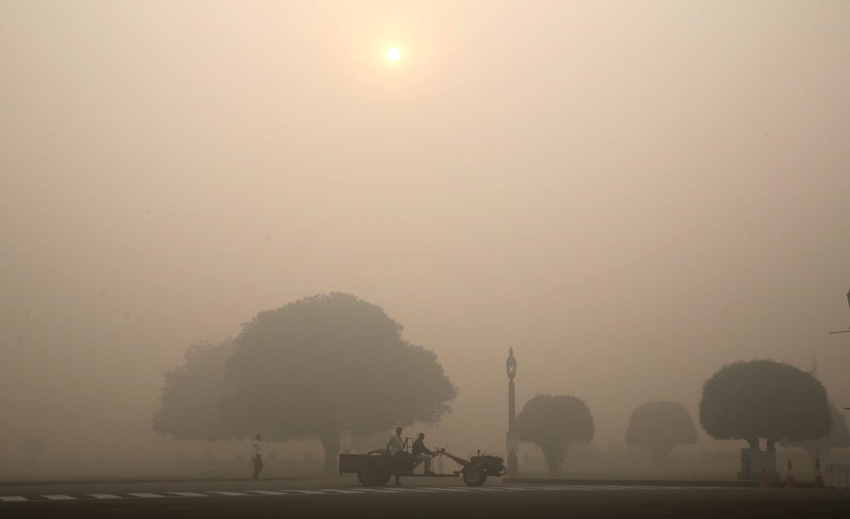 Indios transitan por una calle en medio de una espesa neblina tóxica, un día después de la celebración del Diwali, "la navidad hindú". (Foto Prensa Libre: EFE).