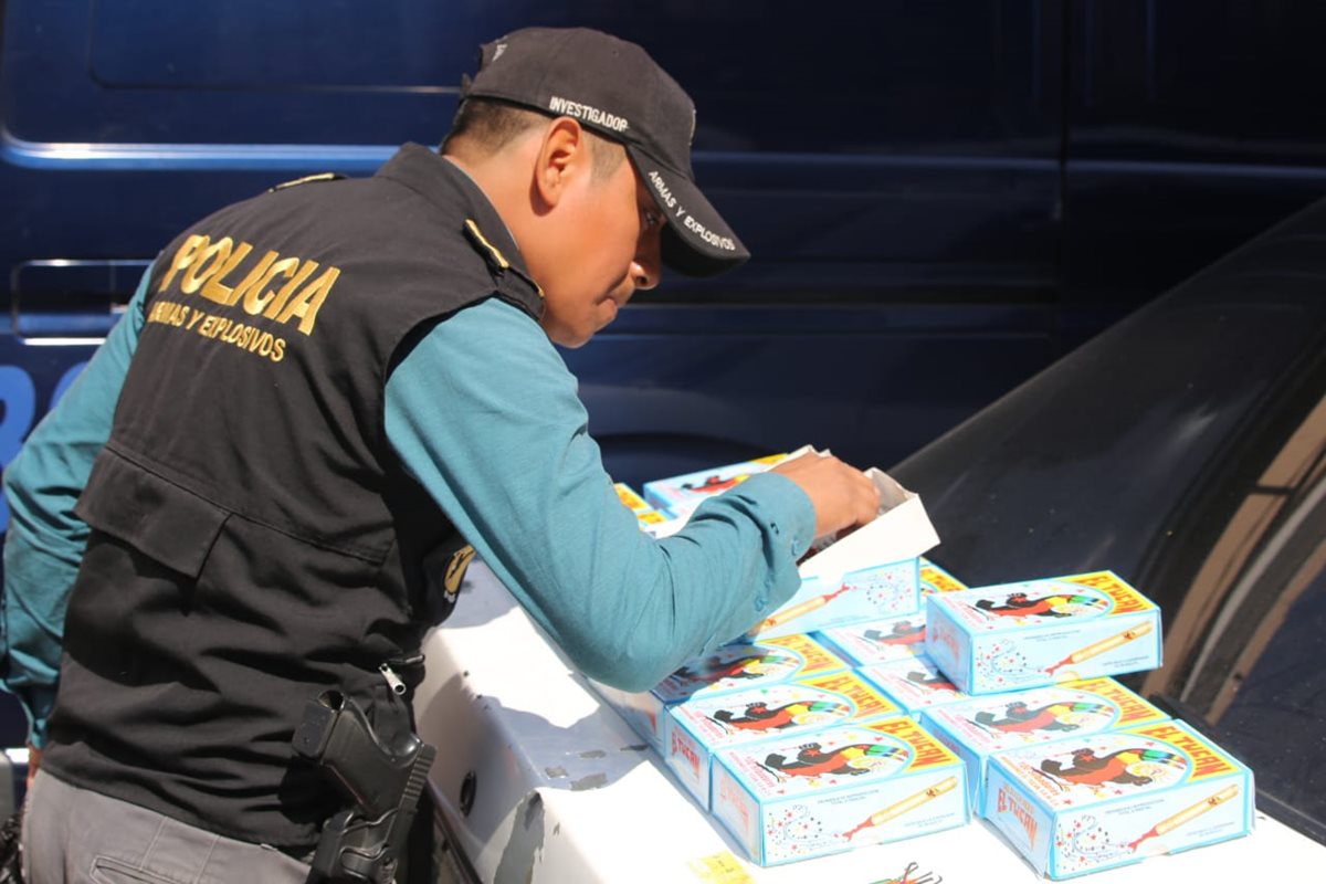 Un agente de la Unidad de Explosivos de la PNC inspecciona un paquete de canchinflines decomisados. (Foto Prensa Libre: Cortesía)