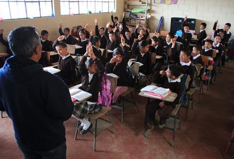 Estudiantes de la Escuela de San José Las Flores, Chiantla,  Huehuetenango, levantan la mano cuando su maestro les pregunta cuántos  de ellos tienen familiares en EE. UU. (Foto Prensa Libre: Mike Castillo)