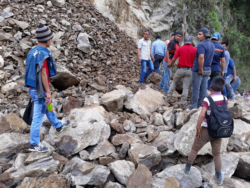 Algunos vecinos de Chajul, Quiché, tratan de caminar entre las enormes piedras que cayeron y bloquean el paso, para llegar a sus destinos. (Foto Prensa Libre: Héctor Cordero)