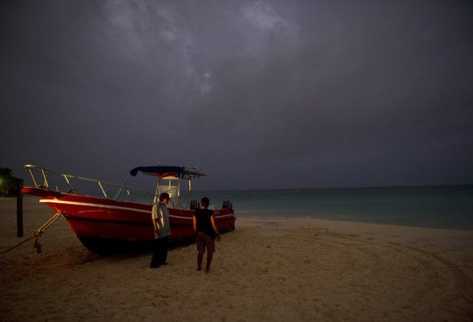 Una pareja de pie cerca de un bote en Playa del Carmen, en el estado de Quinta Roo, México. (AFP).