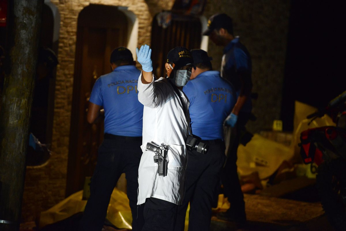 Fiscales y autoridades trabajan en el lugar donde ocurrió la masacre. (Foto Prensa Libre: AFP).