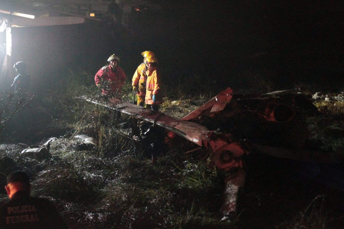 Bomberos rescatan los cuerpos de los dos tripulantes del helicóptero siniestrado. (Foto Prensa Libre: EFE).
