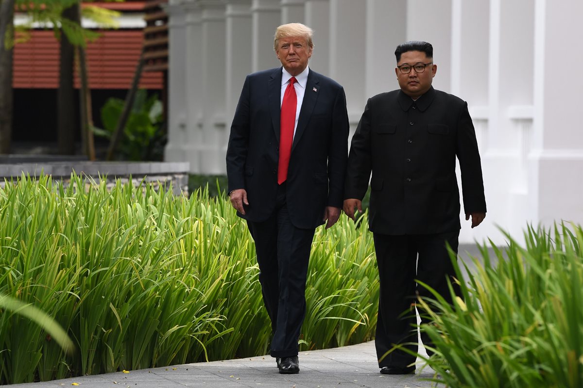 Kim Jong Un (d) acompaña a Donald Trump durante una pausa en la cumbre entre EE. UU. y Corea del Norte, en Singapur. (Foto Prensa Libre:AFP).