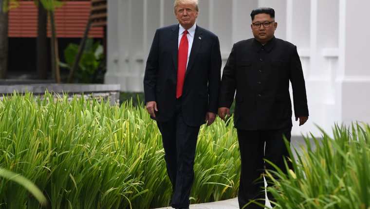Kim Jong Un (d) acompaña a Donald Trump durante una pausa en la cumbre entre EE. UU. y Corea del Norte, en Singapur. (Foto Prensa Libre:AFP).