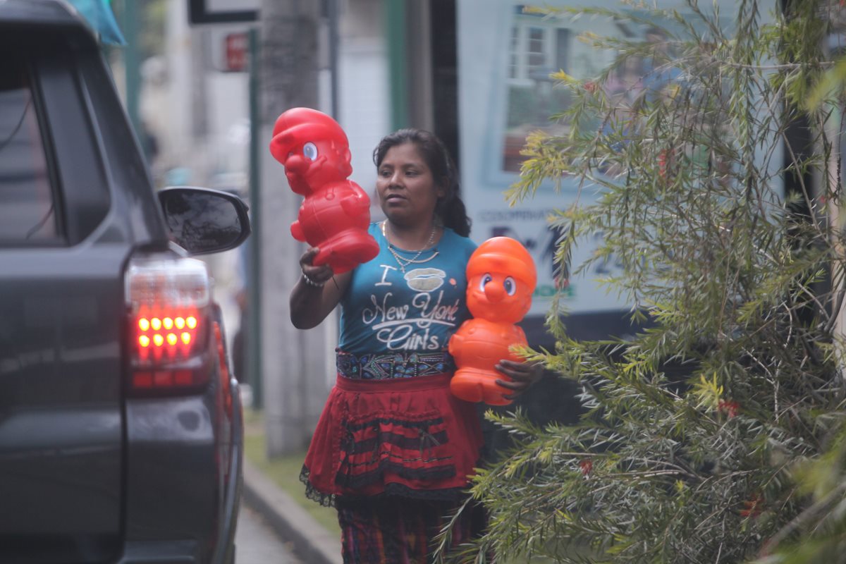 Una mujer ofrece a los automovilistas alcancías plásticas del personaje Mario Bros a Q15, en la zona 9. (Foto Prensa Libre: Erick Ávila)