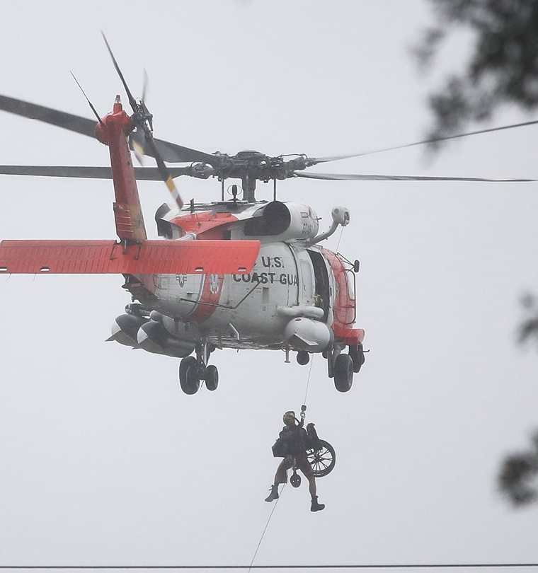 Un helicóptero traslada una silla de rueda a bordo después de levantar a una personaafectada por las inundaciones. (AFP).