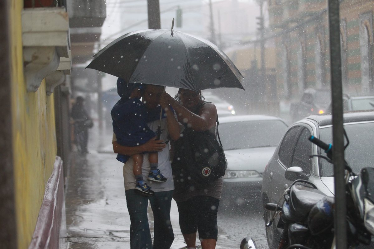 Guatemaltecos se cubren de la lluvia en la ciudad capital. (Foto Prensa Libre: Hemeroteca PL)