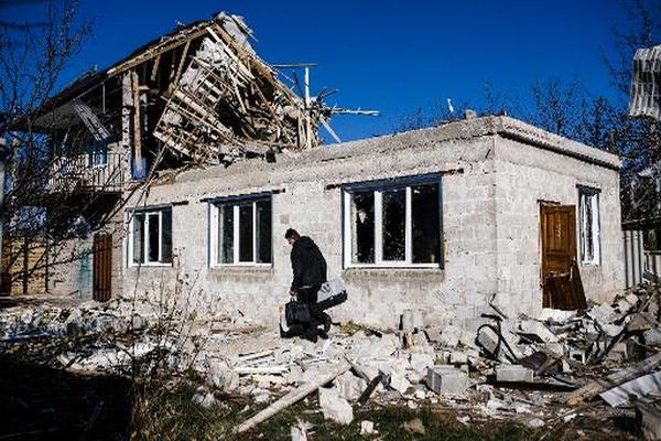 Un hombre con sus pertenencias junto a su casa destrozada tras un bombardeo en Kuybeshevski. (Foto Prensa Libre: AFP)
