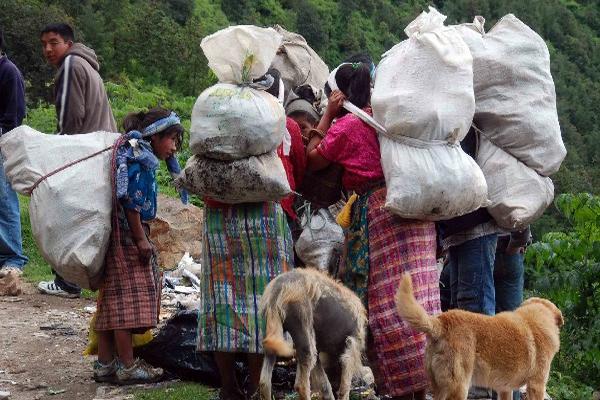 Pobladores de Santa María Chiquimula, Totonicapán, cargan costales de plástico llenos de desechos que venden para llevar alimento a sus familias.