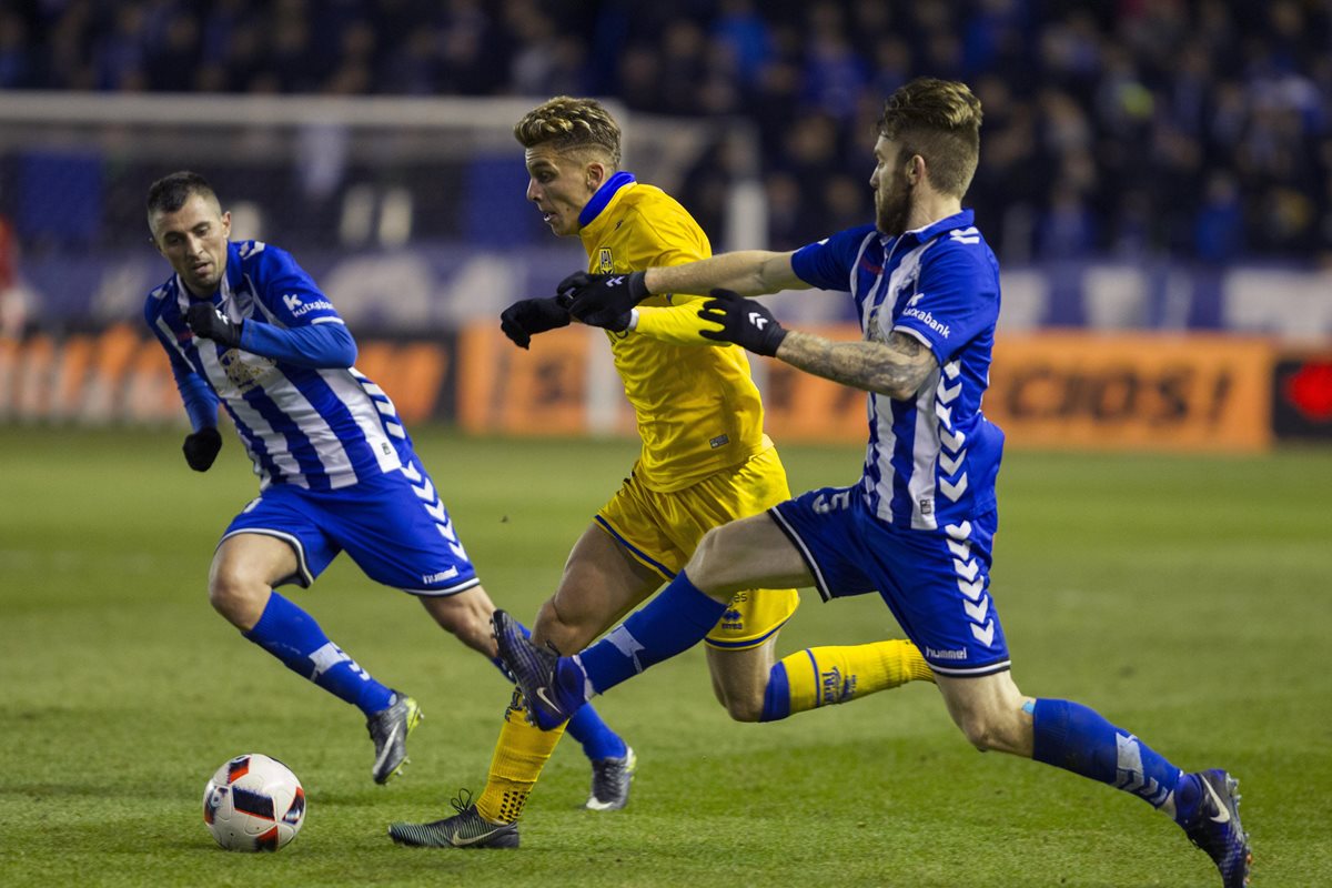 Iván Alejo (c) trata de quedarse con el balón ante los jugadores serbios del Alavés, Nenad Krsticic y Aleksandar Katai. (Foto Prensa Libre: EFE)