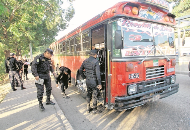 Agentes de la PNC revisan un autobús atacado en la zona 6. (Foto Prensa Libre: Hemeroteca PL)