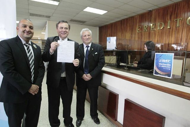 Juan Solorzano, jefe de la SAT, Luis Velásquez, presidente CHN, Lionel López Valdés, viceministro de Finanzas, muestran hoja de actualización de RTU realizada en agencia SAT ubicada en el banco. (Foto Prensa Libre: Carlos Hernández)